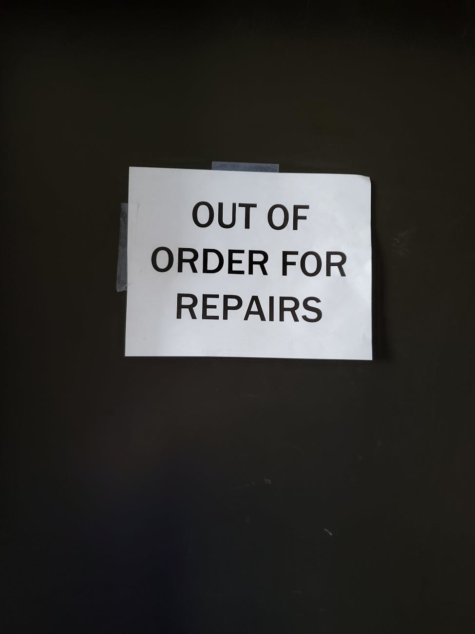 close up of a note stuck to a wall saying out of order for repaires