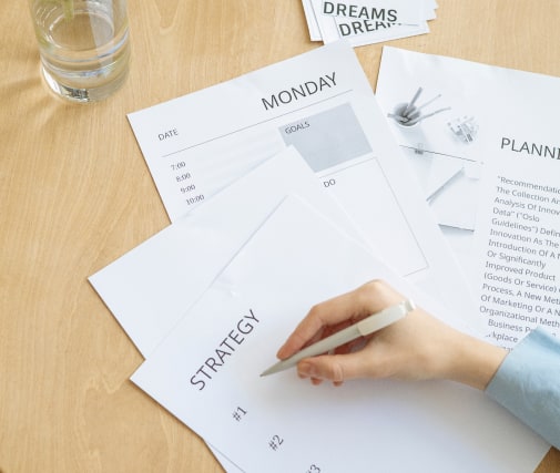 person writing on stationary at a desk